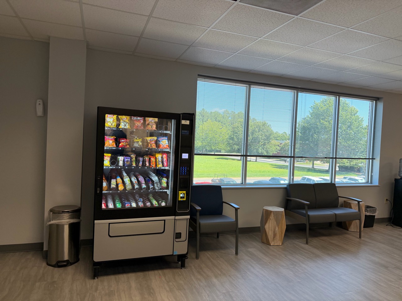Stocked Blue Pearl snack and drink machine beside seating in a bright lobby